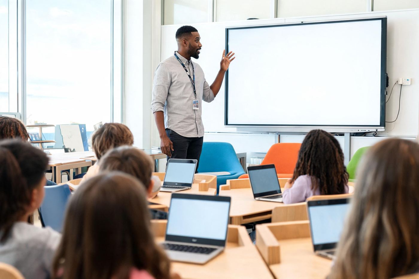 A teacher mid-explanation beside a large classroom display